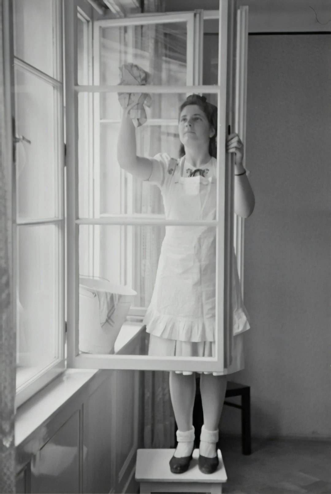 about-us-01 Person using spray bottle and cloth for cleaning a kitchen shelf, ensuring hygiene and cleanliness.